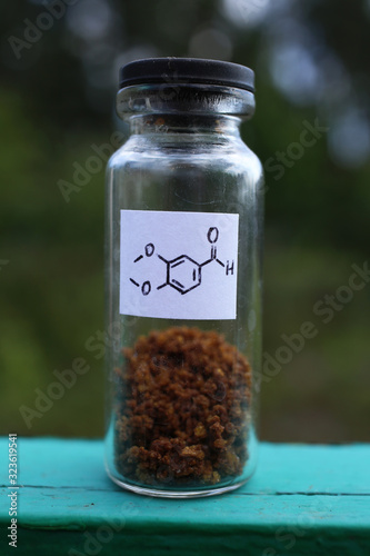 Brown crystalline, organic substance, aromatic aldehyde for use in cosmetics, in a glass jar.