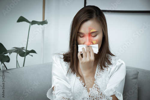 Asian women wear white nightgown & long sleeve satin robe with floral lace feeling sinusitis at night. A girl suffers from sinus in the living room.