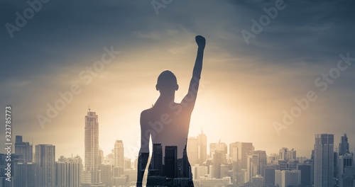 confident young woman with fist in the air facing the city. People power and strong young woman concept 