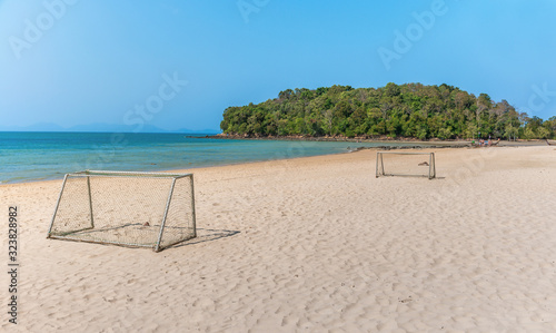 Small football field on white sand beach with blue sky and ocean on sunny day.