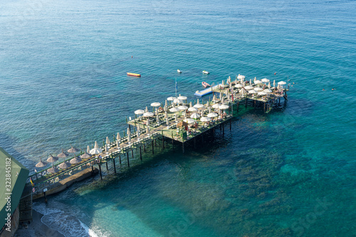 Pier filled with the sun loungers and parasols in the blue sea