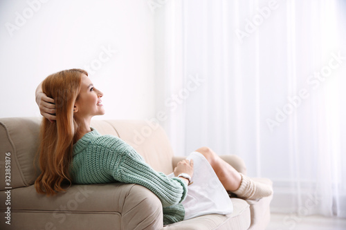 Young woman relaxing on couch at home. Space for text