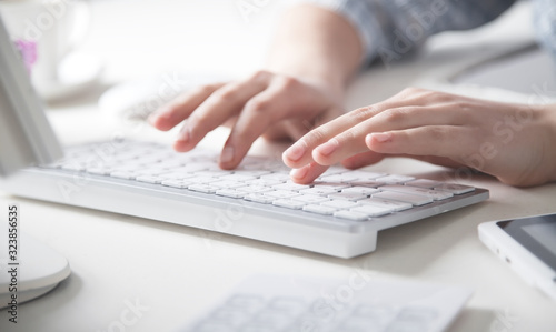 Hands typing on computer keyboard in office desk.