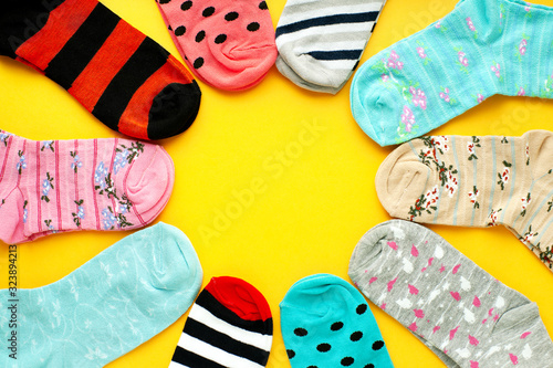 Bright socks on a yellow background. Socks folded in the form of the sun on a yellow background. Socks of different sizes and colors for the cold seasons. Warm clothing.