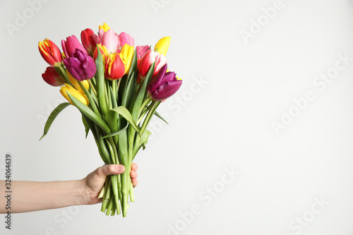 Woman holding beautiful spring tulips on white background, closeup. Space for text