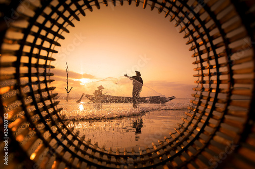 Two fishermen are fishing at the lake during sunset in Chonburi, Thailand.