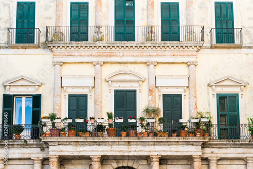 historical building with shutters, balcony and flower pots. Altamura, Italy
