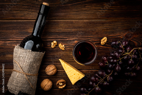 Red wine, grape, cheese and walnut on dark wooden background.