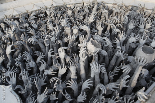 Hands of people pulled with entreaty. Wat Rong Khun (White Temple) in Chiang Rai city, Thailand. Religious traditional national Thai architecture. Landmark, architectural monument of Chiang Rai. Money