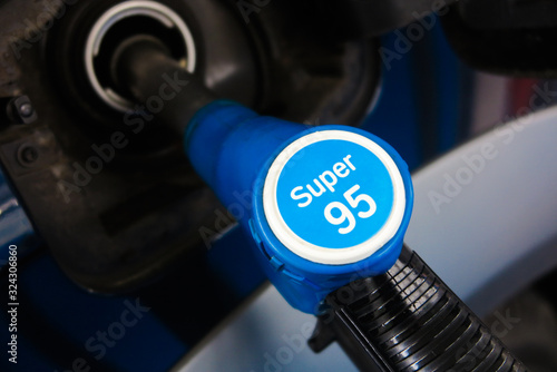 Close up of isolated petrol nozzle in opening of car tank filling with super 95 octane