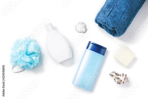 Moisturizing shampoo, shower gel, blue sponge, soap, rolled towel and seashells. Flat lay photo natural spa cosmetics, organic bath products. Toiletries view from above