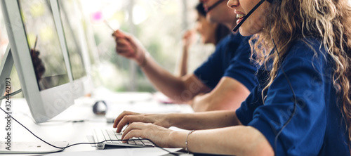 Group of happy smiling business operator customer support team phone services working with headset and computer at call center