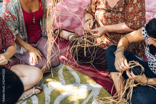 Different ages females weaving bascets on the craft workshop, sitting on a carpet on a flour. Diversity and inclusion in creativity. Women community. Australia multicultural.