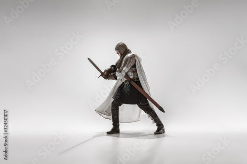 Brave armored knight with professional weapon fighting isolated on white studio background. Historical reconstruction of native fight of warriors. Concept of history, hobby, antique military art.