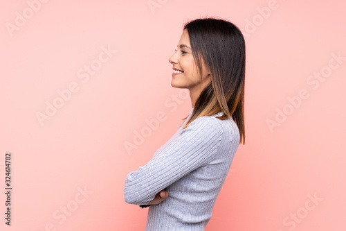 Woman over isolated pink background in lateral position