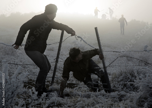 Two men escape from enemies through fence