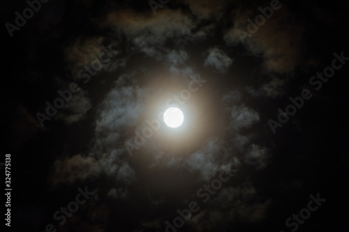 Moon on in the night sky among clouds; natural background of the night sky with the moon