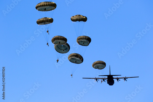 Military parachutist paratroopers jumping out of an air force airplane.