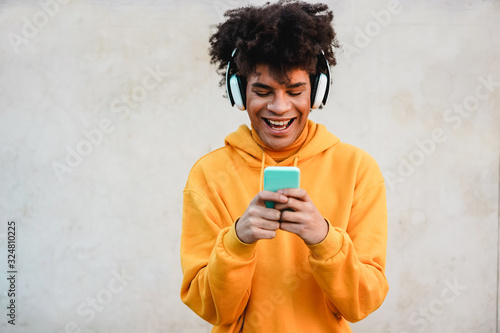 Happy african millennial guy listening music playlist with smartphone app outdoor - Young man having fun with technology trends - Tech, generation z and stylish concept - Focus on face