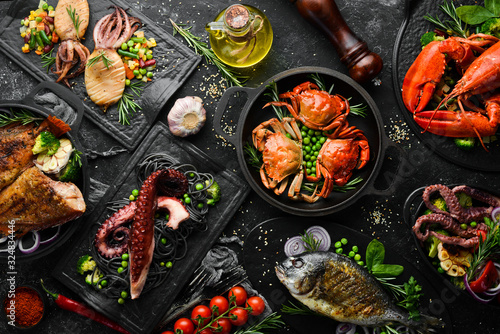 Set of seafood dishes. Fish, squid, octopus on a black stone background. Top view. Free space for your text.