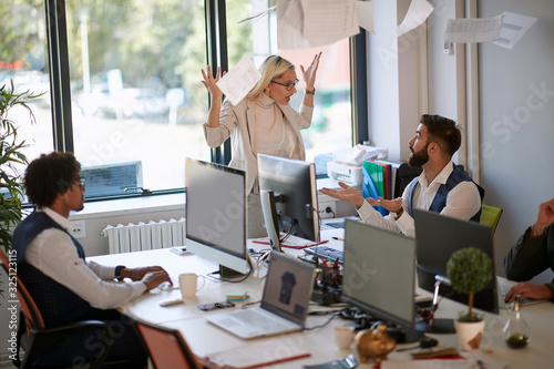 surprised employee explaining to angry female boss who is throwing papers in the ear in front another employee. business, stress, mobbing concept