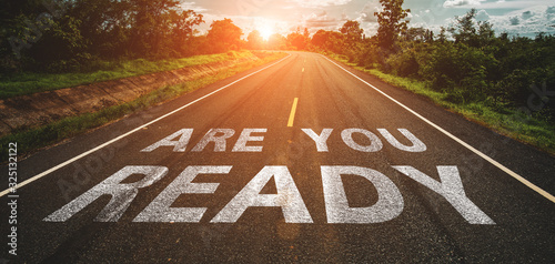 Are you ready written on highway road in the middle of empty asphalt road at beautiful blue sky.