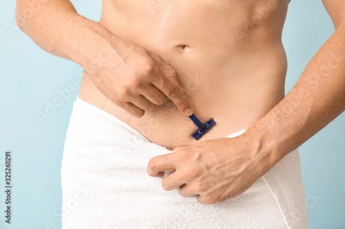 Handsome young man shaving his body on color background, closeup