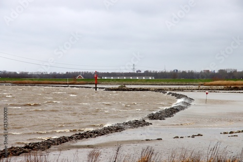 Water blown over lines of stone at river Hollandsche IJssel at Nieuwerkerk in the Netherlands