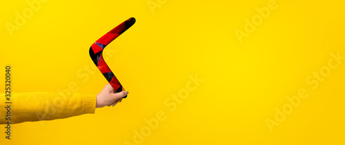 boomerang in female hand over yellow background, panoramic mock-up with space for text