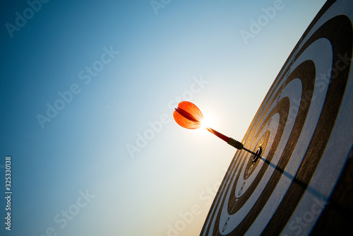 Close up shot red darts arrows in the target center on dark blue sky background. Business target or goal success and winner concept.