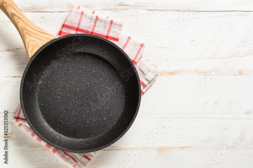 Frying pan or skillet on white wooden table.