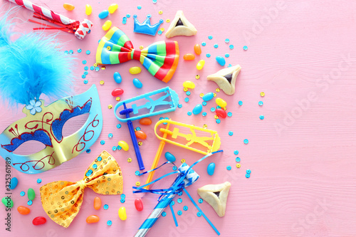 Purim celebration concept (jewish carnival holiday) over wooden pink background. Top view, flat lay