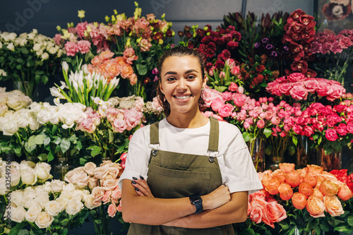 Woman florist standing in flower shop. Female florist in apron standing with her arms crossed.