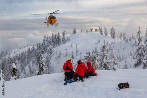 North Vancouver, British Columbia, Canada. North Shore Search and Rescue are rescuing a man skier in the backcountry of Seymour Mountain with a helicopter in winter during sunset.