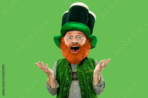 Astonished, surprised. Excited leprechaun in green suit with red beard on green background. Funny portrait of man ready to party. Saint Patrick day, human emotions, celebration, traditional holidays.