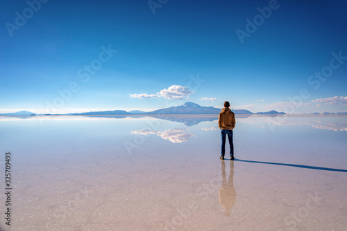 Young man watching the scenery and miror effect in Salar de Uyuni (Uyuni salt flats), Potosi, Bolivia, South America