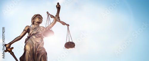 Legal law concept statue of Lady Justice with scales of justice sky background