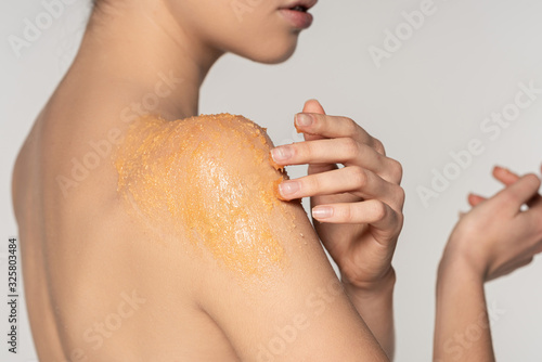 cropped view of girl applying sugar scrub on shoulder, isolated on grey