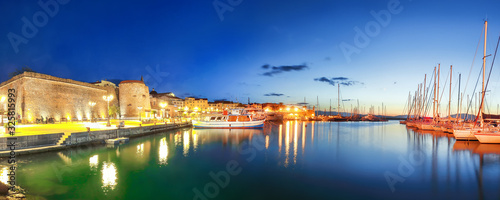 Night view of the Alghero Marina yacht port at the Gulf of Alghero with anchored sailboats