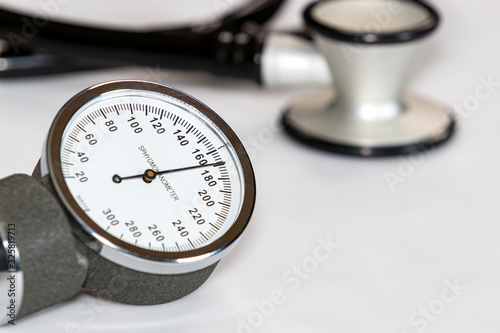 Closeup of blood pressure cuff gauge with high systolic reading of 170 mmHg. Stethoscope in background