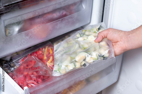 Freezer and frozen vegetables, a person taking food from the freezer