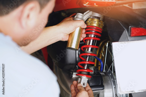 motorcycle mechanic check and Change rear shock absorber big scooter ,motorcycle maintenance and service and repair concept in garage