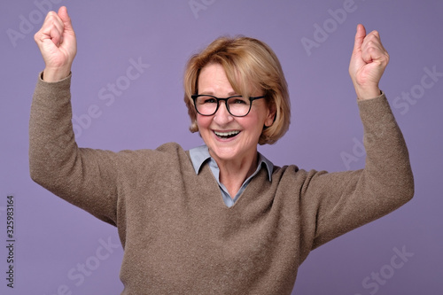 Mature senior woman doing a winner gesture holding fists up enjoying the moment