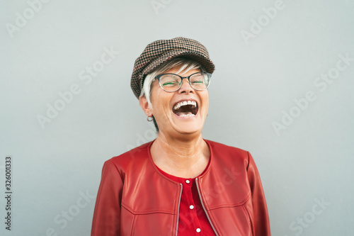 Happy senior woman laughing outdoor - Trendy mature person having fun during retired time - Elderly people lifestyle concept