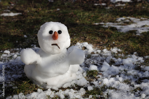 Snowman is melting in the sun. Thaw, warm winter, early spring, global warming, climate change. Spring background.