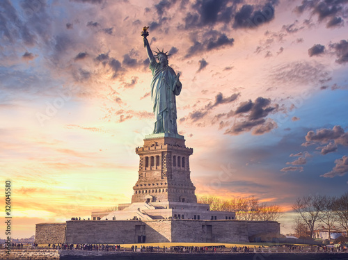famous statue of liberty and dramatic sky at sunset with orange colors. Travel concept
