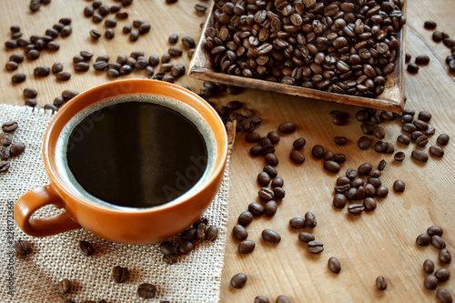 Czarna kawa w brązowej filiżance na tle ziaren kawy