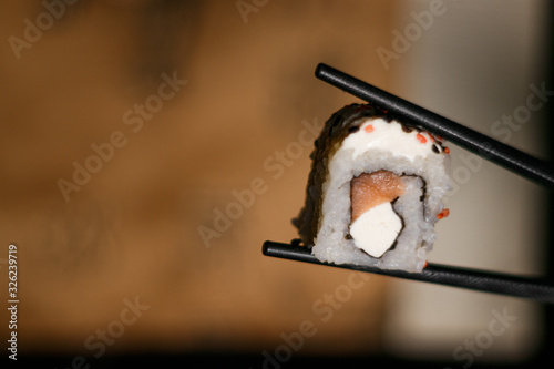 Rollo de Sushi sostenido por palillos chinos
