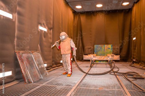 the worker processes the sandblast in the chamber dirty part before painting