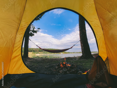 view form camping tent on campfire with hammock near lake